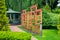 Vertical wooden pergola in climbing roses garden with stone brick walkway.