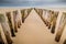 Vertical wooden planks in the sand of an unfinished wooden dock at the beach under a cloudy sky