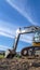 Vertical Yellow excavator with continuous tracks digging soil at a construction site