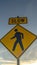 Vertical Yellow Slow sign and pedestrian crossing sign against cloudy sky at sunset