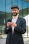 Vertical. young adult man using a cellphone app at workplace. Bearded cool guy having fun with a smartphone device