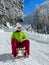 VERTICAL: Young Caucasian woman sleds down a groomed slope in the sunny Alps.