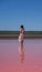 Vertical of a young female in a white dress standing in Pink Lake in Port Gregory, Australia
