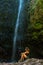 Vertical of a  young woman sitting in the waterfall at the Levada do Caldeirao Verde, Madeira.