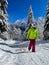 VERTICAL: Young woman sledding in the Alps walks up a groomed forest trail.