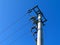 Vertically dropping electrical cables concrete pole. clear blue sky