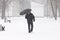 Very bad weather in a city in winter: terrible heavy snowfall and blizzard. Male pedestrian hiding from the snow under umbrella