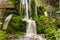 Very beautiful artificial waterfalls with living water and growing moss. Water flows from above, splashes and drops around