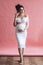 Very beautiful caucasian pregnant woman with make up and dark hair in white dress holds her belly, portrait of future