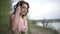 Very beautiful smiling girl in light pink dress relax on the swing at the lake beach