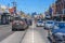 A very busy Sydney Road in Brunswick on a sunny day, with the Melbourne city skyline in the distance