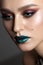 A very close up portrait of a beautiful young girl with bright colorful trendy smoky eyes and blue sparkle lips.