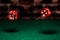 A very close up shot of 2 dice rolling on a green felt table top in very crisp focus, showing 2,4,5 and 6 on the faces.  The