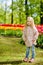 very cute beautiful girl blonde in pink coat stands near a flower bed of red tulips in a Park and smiling