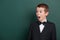 Very emotional school boy portrait near green blank chalkboard background, dressed in classic black suit, one pupil, education con