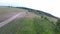 A very fast flight of a drone or quadcopter with maneuvers over a field with grass. High-speed flight.