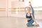 Very flexible caucasian woman doing stretching exercises in dance class with mirrors and barre.
