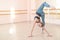 Very flexible caucasian woman doing stretching exercises in dance class with mirrors and barre.