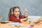 Very good schoolgirl girl sitting at the table. During this, he holds his hand on the books that stand on the table