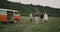 Very happy running and jumping group of friends , in the middle of field, beside orange vintage van