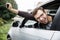 Very happy young man is peeking from the car window while looking at the camera. He is holding the keys at his right hand. Lottery