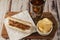 Very high view of a hotdog with chimichurri sauce with soda and potato chips on a rustic table. Fast and junk food concept