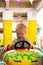 A very joyful and happy little blond boy of three years old is riding in a yellow car with a green car in the summer Riviera