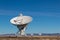 Very Large Array radio antenna dish close with others in distance, blue sky