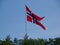 a very large flag flying high over trees and sky with blue skies