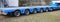 very long blue truck with six axles of wheels