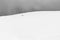 A very minimalistic view of two distant people over a mountain covered by snow, near a fence