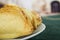 Very nice empanadas stacked up on white plate, perfect golden color, green table cloth and blurry street background