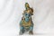 Very old little lord krishna doll with traditional oranments painted in blue colour placed in a white backdrop