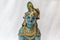 Very old little lord krishna doll with traditional ornaments painted in blue colour placed in a white backdrop