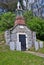 Very old mausoleum built into the side of a hill with steeple, tombstones, and wrought iron fence