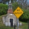 Very old mausoleum built into the side of a hill with steeple, tombstones, wrought iron fence, and no outlet sign