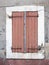 Very old reddish brown painted shutters on window in medieval provence house in luberon area
