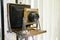 Very old rustic vintage large format camera as decoration in a room again white background. Side view