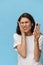 a very pensive woman stands on a blue background in a white T-shirt with a fashionable phone in her hands and looks at