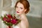Very pretty sophisticated red-haired girl with a bouquet in hand