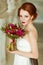 Very pretty sophisticated red-haired girl with a bouquet in hand