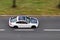 Very quickly driving white ecological solar electric car on a city street. The image is taken with a strong motion blur effect