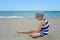 Very serious cute little girl sitting on the beach