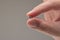 Very small metal bearing ball held between fingers by Caucasian male hand. Close up studio shot, isolated on gray background