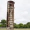 Very tall rusty water tank with two men climbing up its ladder.