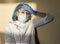 A very tired woman doctor in a protective medical mask, glasses and gloves touches her forehead