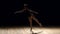 Very young ballerina posing on a black background.