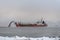 Vessel engaged in dredging at sunset time. Hopper dredger working at sea. Ship excavating material from a water environment