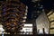 Vessel  TKA, a spiral endless staircase with the Shed near it, skyscrappers behind. Night view with bright lights. Hudson Yards