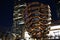 Vessel  TKA, a spiral endless staircase, skyscrappers behind. Night view with bright lights. Hudson Yards, Manhattan`s West Side